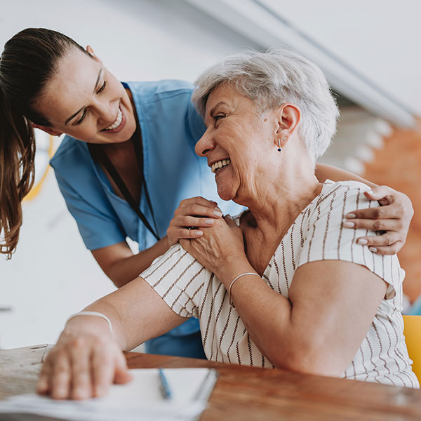 ill elderly woman and young lady smiling at each other